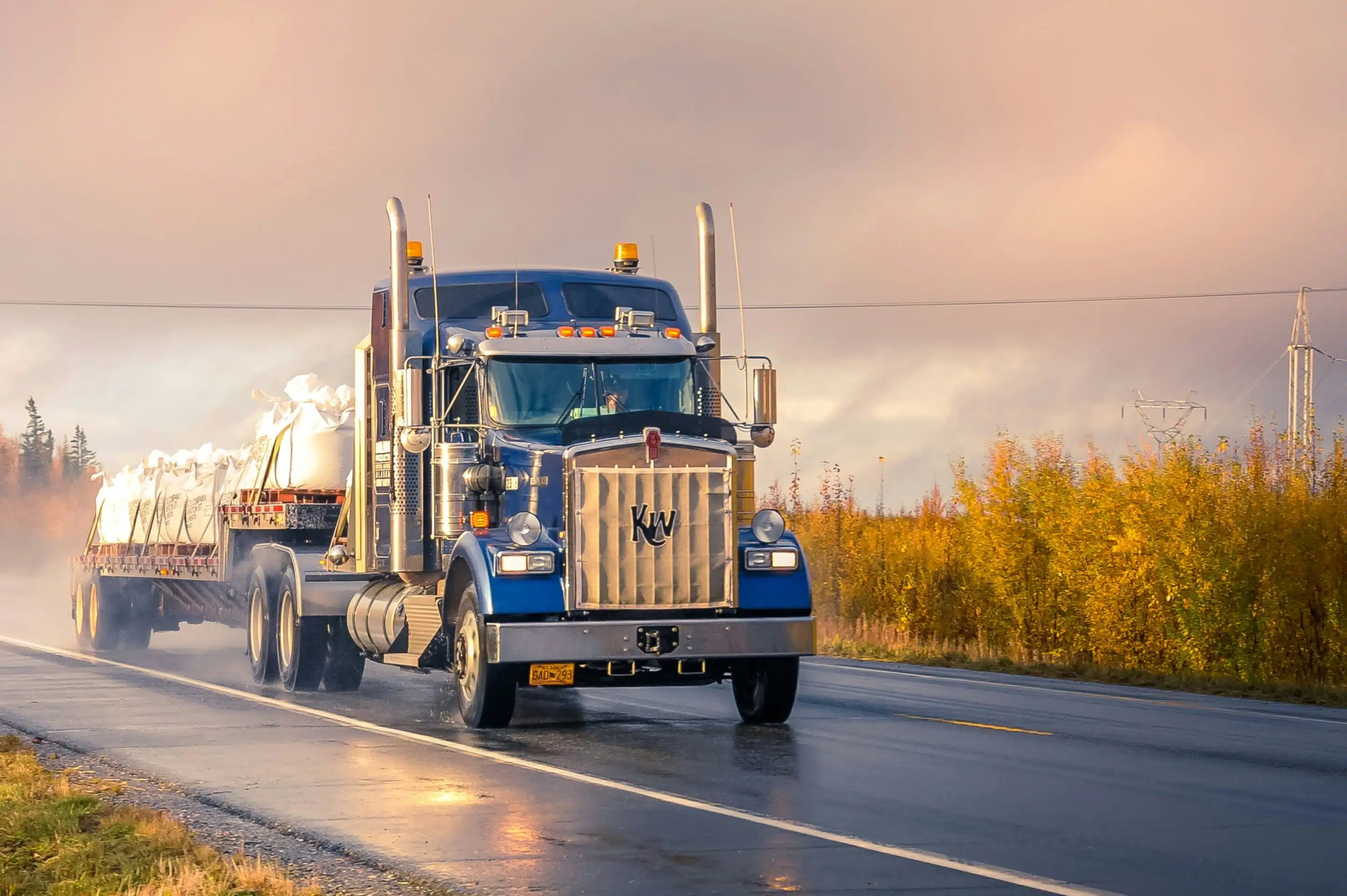 A Semi driving down the highway with a load of industrial sand bags. 