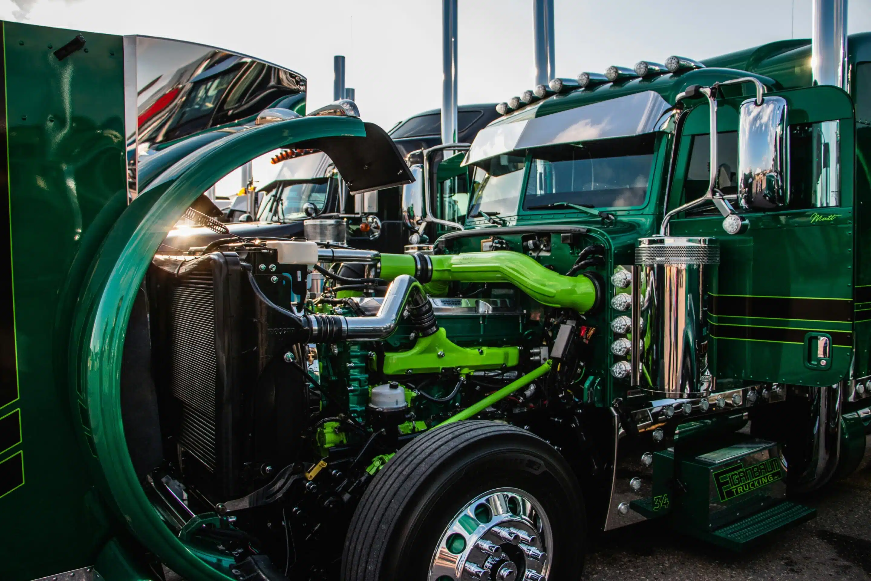 A Green semi with its hood open exposing the engine for inspection.