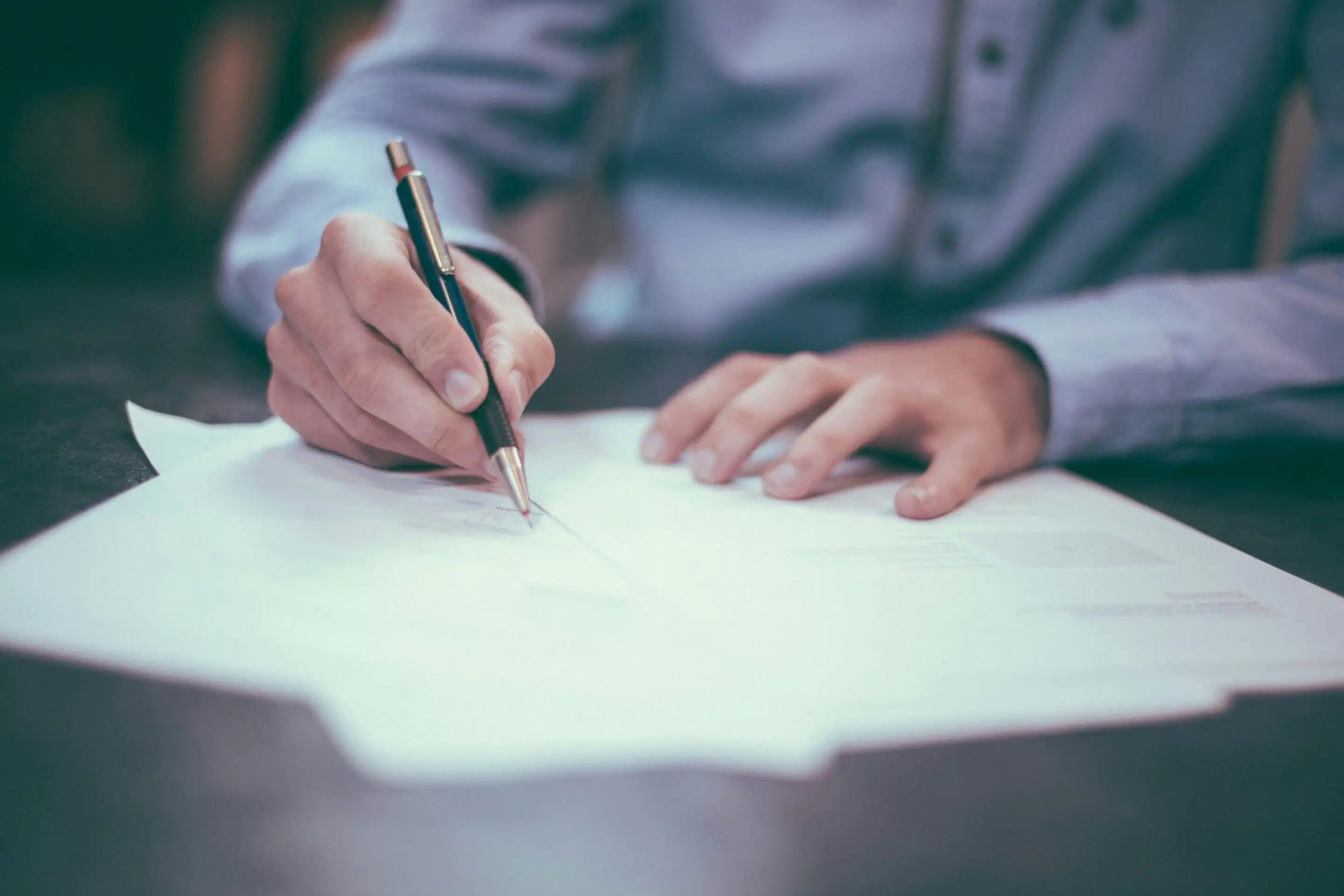Person filling out Application with a pen.