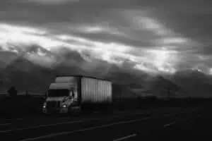 Black and white photo of semi driving in mountains.